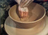 Sponging excess water and smoothing the surface of the wheel thrown pottery.